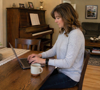 Woman types on laptop to request service from Rosenberg Piano
